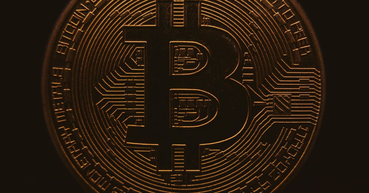 Close-up bitcoin coin in dark setting representing crypto volatility.