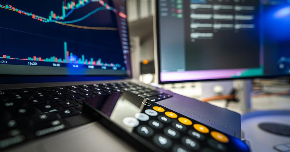 Trader reviewing inflation and market data on laptop and external display.